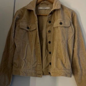 Beige manchesterjacka från Jacqueline de Yong - Säljer en snygg beige manchesterjacka från Jacqueline de Yong. Jackan har knappar framtill och två bröstfickor med knappstängning. Perfekt för en stilren look!