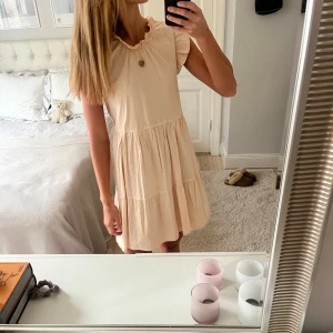 Beige klänning med volanger - Helt underbar klänning med volangdetaljer 💕💕🩷 Perfekt till sommaren, både till stranden och finare middagar. Köptes för några år sedan i en butik i Frankrike, men har tyvärr klippt bort lappen så vet varken storlek eller märke. Sitter  som en S/M 🌺