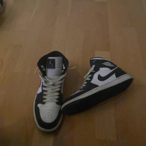 Nike Air Jordan 1 Mid - Säljer ett par Nike Air Jordan 1 Mid i svart och vit färg. Skorna är i helt ny skick endast använda en gång, nypris ligger på 1799 o mitt pris är endast 799, box ingår givetvis, vi snabb affär kan priset diskuteras, tveka inte på att höra av er😃