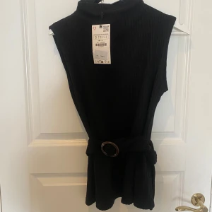 Svart ribbad topp med bälte - Snygg svart ribbad topp med bälte i midjan från Zara. Toppen är helt oanvänd i storlek S. Ny pris 299.90 kr  mitt pris 139 🥰🥰