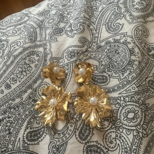 Guldörhängen med pärldetaljer - Superfina guldörhängen formade som blommor med en vacker pärldetalj i mitten. Dom är från SHEIN och är endast använda en gång. Skriv vid intresse