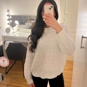 Vit stickad tröja - Säljer en mysig vit stickad tröja med ett luftigt mönster. Tröjan har långa ärmar och ribbstickade muddar vid ärmslut och nederkant. Perfekt för kyliga dagar!