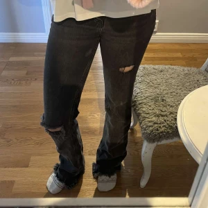 Grå/svarta  jeans med slitningar - Snygga grå/svarta jeans med slitningar på knät och låret. Väldigt långa i benen. 