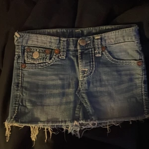 blå jeanskjol från true religion - snygga blå kjol från true religion med fransiga kanter och coola bakfickor med knappar. jag köpte denna seconhandn utomlands men har inte använts så mycket då den inte passar som jag vill. pris kan diskuteras 