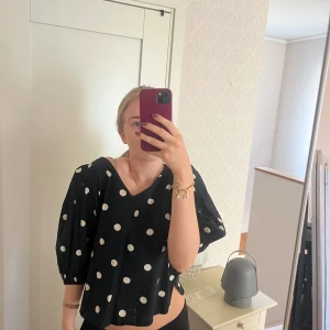 Svart blus med vita prickar - Säljer en svart blus med vita prickar och trekvartsärmar. Blusen har en lös passform och en rund hals, i M! Från Gina tricot!