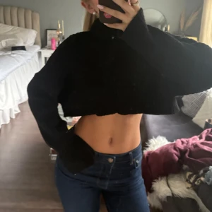Svart croppad stickad tröja - Säljer en svart croppad stickad tröja med långa ärmar. Perfekt för en trendig och avslappnad stil. Passar bra till jeans eller kjol för en cool look.