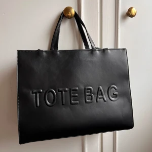 Svart tote väska  - Strukturerad axelväska, har både handtag och ett längre band om man vill bära den crossbody. Perfekt storlek som en vardagsväska/ skolväska då dator får plats.