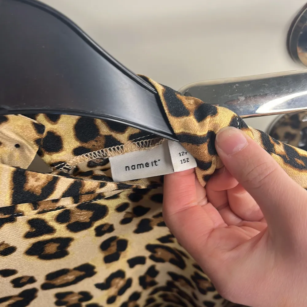 Säljer en cool leopardmönstrad klänning från Name It. Klänningen har en volangdetalj vid fållen och är ärmlös, vilket ger en trendig look. Perfekt för den som vill sticka ut med ett djärvt mönster.. Mekot.