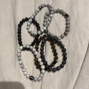 Set med pärlarmband i olika färger - Säljer ett set med flera elastiska pärlarmband i olika färger. Armbanden har pärlor i svart, vit, grå och brun nyans, vissa med marmorerat mönster. Perfekt för att mixa och matcha efter stil och humör. 150 för alla eller 40 styck.