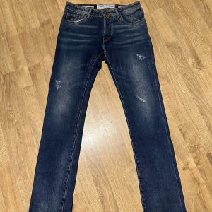 Blå jeans från Jacob Cohën - Snygga blå jeans från Jacob Cohën med klassisk femficksdesign och slitna detaljer. De har en knappgylf och en läderpatch med logotyp baktill. Perfekta för en avslappnad stil. Modellen är J688 och är en slim modell, dessa är aldrig använda och har även kvittot från kvar. Storlek 30📏