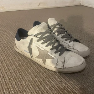 Golden Goose Superstar skor - Riktigt snygga beiga Golden Goose Superstar skor med blåa detaljer i storlek 45. Lite slitage på hälen men i övrigt i mycket gott skick.