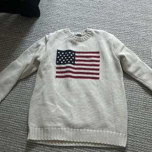 Beige stickad tröja från Brandy Melville - Säljer en beige oversize stickad tröja från Brandy Melville med ett stort amerikanskt flaggmönster på framsidan. Tröjan är i nyskick och knapp använd! Nypris ca 420 