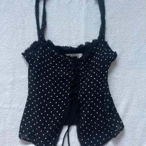 Svart prickig topp från Zara - Snygg topp från Zara med smala axelband och snörning framtill. Använd men fortfarande i fint skick! 
