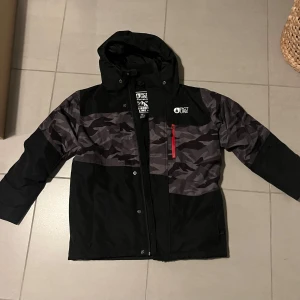 Svart och grå jacka från Picture - En svart och grå skidjacka från Picture. Passar ålder 10-13. Fick för liftkort på armen. 