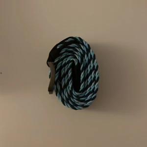 Blått flätat bälte - Snyggt blått flätat bälte med ett coolt mönster. Perfekt för att ge din outfit en extra touch. Bältet är runt 100cm långt!