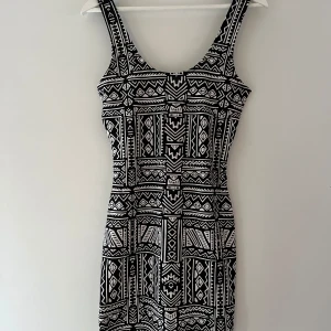 Svartvit mönstrad klänning - Snygg svartvit klänning med geometriskt mönster. Den är ärmlös och har en tight passform som framhäver figuren. Perfekt för en stilren look. 