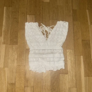 Vit ärmlös topp med knytning - Säljer en jättefin topp till fester eller sommarens väder! Testad en gång men kände att den var lite liten. Öppen i ryggen med knytning i nacken, funkar superfint med en kjol!