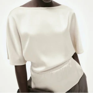 Krämvit blus med korta ärmar - Elegant krämvit blus med korta ärmar och en lös passform. Perfekt för både vardag och festliga tillfällen. Den har en enkel och stilren design som gör den lätt att matcha med olika outfits. Helt oanvänd med lappar kvar. Den är endast testad annars är den helt som ny. Har dock observerat en liten fläck (se sista bilden), men det är inget som riktigt syns. Slutsåld i alla storlekar och kommer nog inte tillbaka i lager.