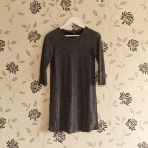 Svart glittrig klänning från Monki, Strl: 34/XS - Snygg svart klänning från Monki med glittrigt mönster. Den har trekvartsärmar och en bekväm passform. Perfekt för en kväll ute eller en speciell tillställning.