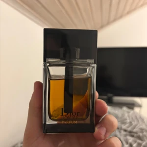 Dior Homme Parfum - Elegant och maskulin parfym från Dior i en stilren glasflaska med svart lock. Doften är intensiv och sofistikerad, perfekt för den som vill göra ett intryck. Svår att få tag på till ett bra pris den är ganska över prisad på olika hemsidor. 