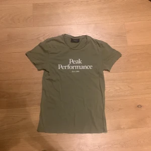 olivgrön t-shirt från Peak Performance - Snygg ogrön t-shirt från Peak Performance med tryck på bröstet. Skick 8/10