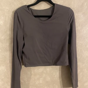 Grå långärmad croppad  topp - Snygg grå croppad topp med långa ärmar. Perfekt för en stilren och modern look. Enkel design som passar till många olika outfits.😚Inbyggd skum-bh i