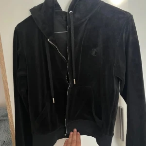 Svart Juicy Couture kofta - Säljer en svart Juicy kofta med dragkedja och huva. dragkedjan har gått sönder så därav priset, men går enkelt att fixa. annars mycket bra skick. Storlek S 