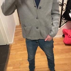 Stickad cardigan - Säljer en stilren stickad cardigan med en exklusiv look. Tröjan har 3 olika fickor med 3 knappar. Den är i fint skick och har mycket kvar att ge.
