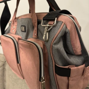 Grå och rosa datorväska med många fack - Praktisk babyväsks i grått och rosa med flera dragkedjeförsedda fack. 