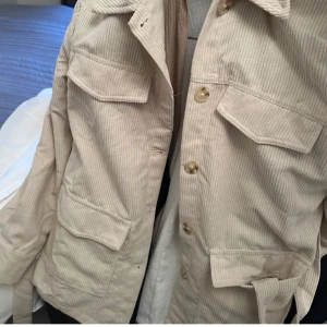 Beige manchesterjacka med knappar - Snygg beige manchesterjacka med knappar framtill och flera praktiska fickor. Perfekt för en avslappnad stil. Jackan har en klassisk krage och är långärmad. Passa på nu när det är gratis frakt(:🫶