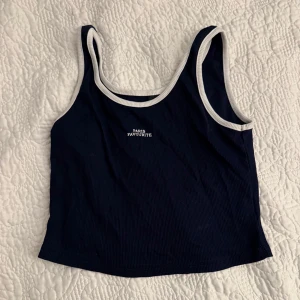 Mörkblå ribbad linnetopp - Snygg mörkblå ribbad linnetopp med vit kant och texten 'Paris Favourite' på bröstet. Skulle säga den är storlek XS/S