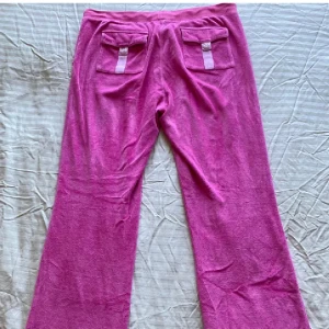 Rosa mjukisbyxor från Juicy Couture - Säljer ett par rosa mjukisbyxor från Juicy Couture. Byxorna har en avslappnad passform med fickor baktill och en mjuk, bekväm känsla. Perfekta för en chill dag hemma eller en avslappnad utflykt.