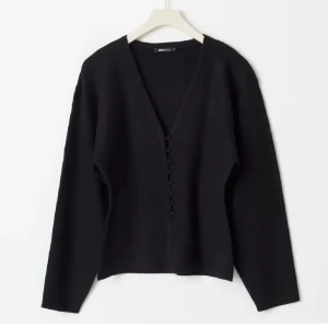 Svart ribbad kofta från Zara - Snygg svart kofta från Ginatricot med knappar framtill. Den har en v-ringad design och långa ärmar, perfekt för en stilren look. Använd en gång💓 slutsåld