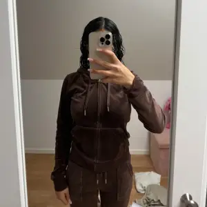 Mysig brun velour hoodie med dragkedja och huva. Perfekt för en avslappnad stil. Den har långa ärmar och en bekväm passform.