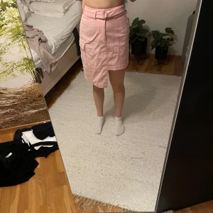 Rosa manchesterkjol från NA-KD - Rosa manchesterkjol från NA-KD med ett bälte i midjan och praktiska fickor på sidan.