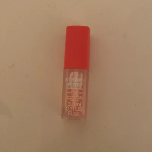 Läppolja med jordgubbsdoft - En läppolja med jordgubbsdoft från P.S. i en liten flaska på 3,3 ml. Den har en röd kork och en applikator för enkel applicering. Perfekt för att ge läpparna en glansig finish och en fruktig doft.