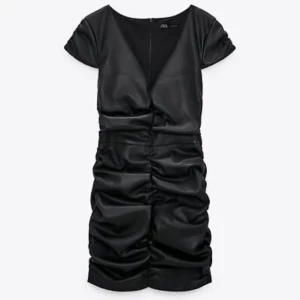 Svart skinnklänning - En svart skinnklänning från Zara. Den är v-ringad framtill och har en dragkedja längs ryggen. Detaljerna gör att passformen ser bättre ut. Pris kan diskuteras