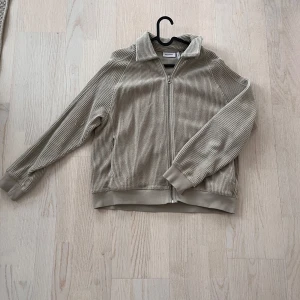 Beige manchesterjacka från Weekday - Säljer en snygg beige manchesterjacka från Weekday med dragkedja framtill. Jackan har långa ärmar och ribbade muddar vid ärmslut.