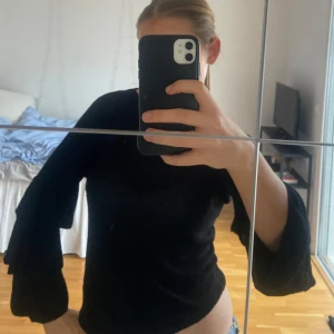 Svart tröja med volangärmar - Snygg svart tunn stickad tröja med volangärmar. I storlek M/S