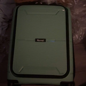 Grön resväska från Normal - Snygg och praktisk grön resväska från Normal med ett stilrent randigt mönster. Perfekt för resor med sitt hårda skal och smidiga hjul. Väskan har en robust design och är lätt att hantera. Finns lås kod till 