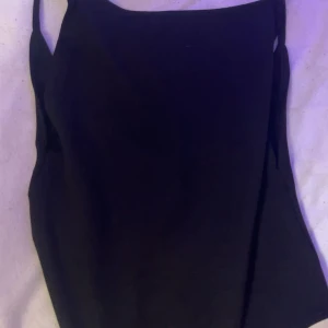 Svart body som är öppen i ryggen  - Snygg svart bodysuit från NLY One med smala axelband och en öppen rygg, använd ett fåtal gånger.