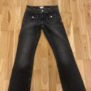 Svarta jeans från Gina Tricot - Snygga svarta jeans från Gina Tricot med vita sömmar och stilrena fickor med knappar. Perfekta för en casual look med en touch av stil. Passar bra till både sneakers och boots.Byxorna är i jätte bra skick aldrig använda. Pris kan diskuteras 