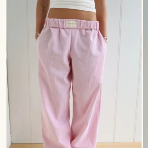 Rosa randiga byxor - Snygga rosa byxor med randigt mönster och loose passform. De är högmidjade med elastisk midja för extra komfort. Perfekta för en avslappnad stil, pyjamas eller en hemma-kläder.  Från studio Seven designs, som gör dem själva - därför är dessa byxor etiskt tillverkade och bra kvalité! Hör gärna av dig med frågor 