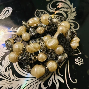Elastiskt armband med pärlor och metallpärlor - Snyggt elastiskt armband med stora krämfärgade pärlor och detaljerade metallpärlor i antik stil. Perfekt för att ge en bohemisk touch till din outfit. Armbandet är stretchigt och passar de flesta handleder.