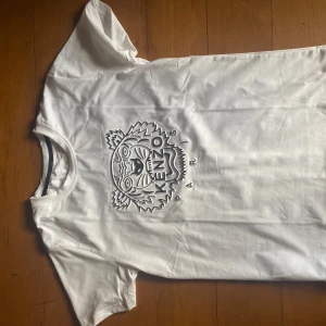 Vit t-shirt med tryck från Kenzo - Snygg vit t-shirt från Kenzo med ett coolt tigertryck på framsidan. Perfekt för en avslappnad stil. Kortärmad och i mjukt bomullsmaterial.