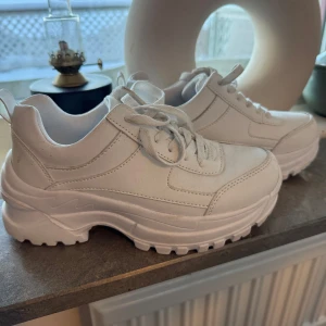 Vita sneakers med tjock sula - Snygga vita sneakers med en rejäl och tjock sula för extra komfort. Skorna har snörning och en modern design som passar perfekt för en trendig look.