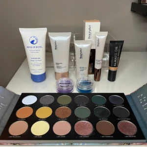 Skönhetskit med ögpnskuggspalett, concealer och primer - Ett set med skönhetsprodukter inklusive Holifrog Omega Gel Wash (oöppnad), BeautyAct Radiant Skin Primer (oöppnad), Multi-Task Dewy Face Gloss (testad en gång), Anti-Dark Circles Concealer färgen 02C (oöppnad) och Smashbox Always On Shimmer i färgen golden shimmer (använd 2-3 ggr). Inkluderar även SUVA hydra liner färgen Blue Steel och hydra fx i färgen Lustre Lilac (använda 2-3 ggr). Kitet innehåller även en fin ögonskuggspalett från Morphe X Ashley Strong (endast 5 färger som är använda 1-2ggr