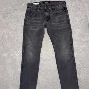 Grå jeansbyxor från Replay - Snygga grå jeansbyxor från Replay i modellen Anbass. De har en klassisk femficksdesign och en bekväm passform. Perfekta för en stilren look. Bra skick 