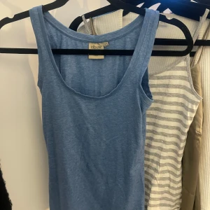 Blå linnetopp från Tribute - Säljer en enkel och stilren blå linnetopp från Tribute. Perfekt för varma dagar med sin ärmlösa design och mjuka material.