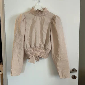 Beige knytblus med öppen rygg - Beige knytblus med öppen rygg från Gina Tricot, använd fåtal gånger, i nyskick